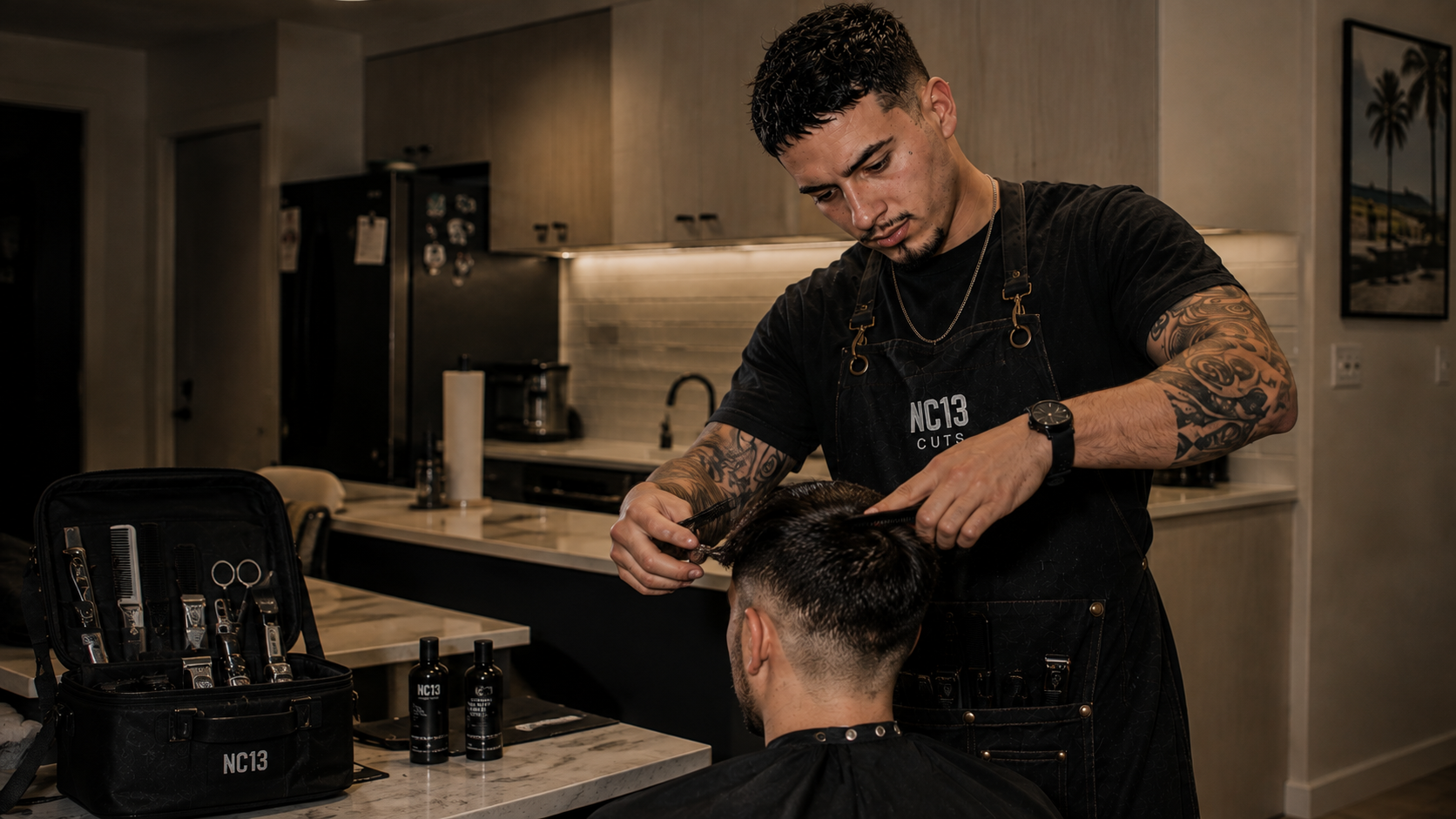 Nathan cutting a client's hair at a kitchen bench, with the NC13 mobile kit of clippers, scissors and combs open beside him.